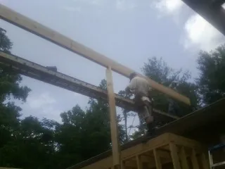 Carpenter setting a ridge beam over a new addition frame — Ice Dam Removal by Roofing Brothers in Minot