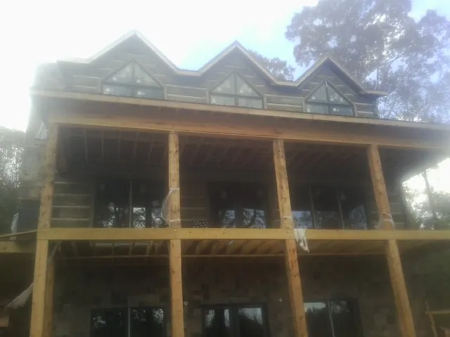 Dormers and porch framing on a large log home under construction — Roof Coating work by our crew in Minot