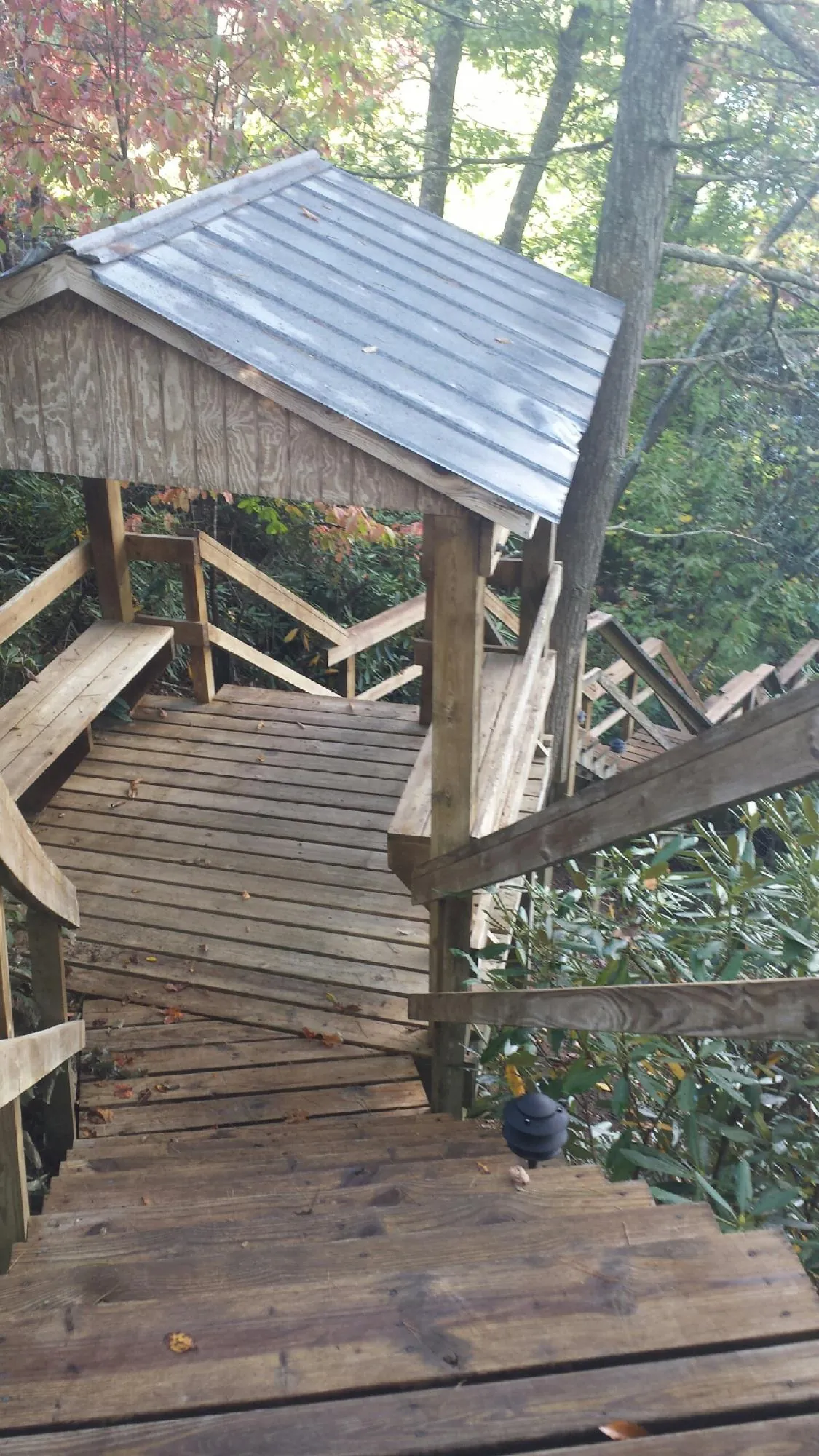 Metal roofed shelter over wooden steps on a wooded walkway — Skylight Repair & Installation work by our crew in Minot