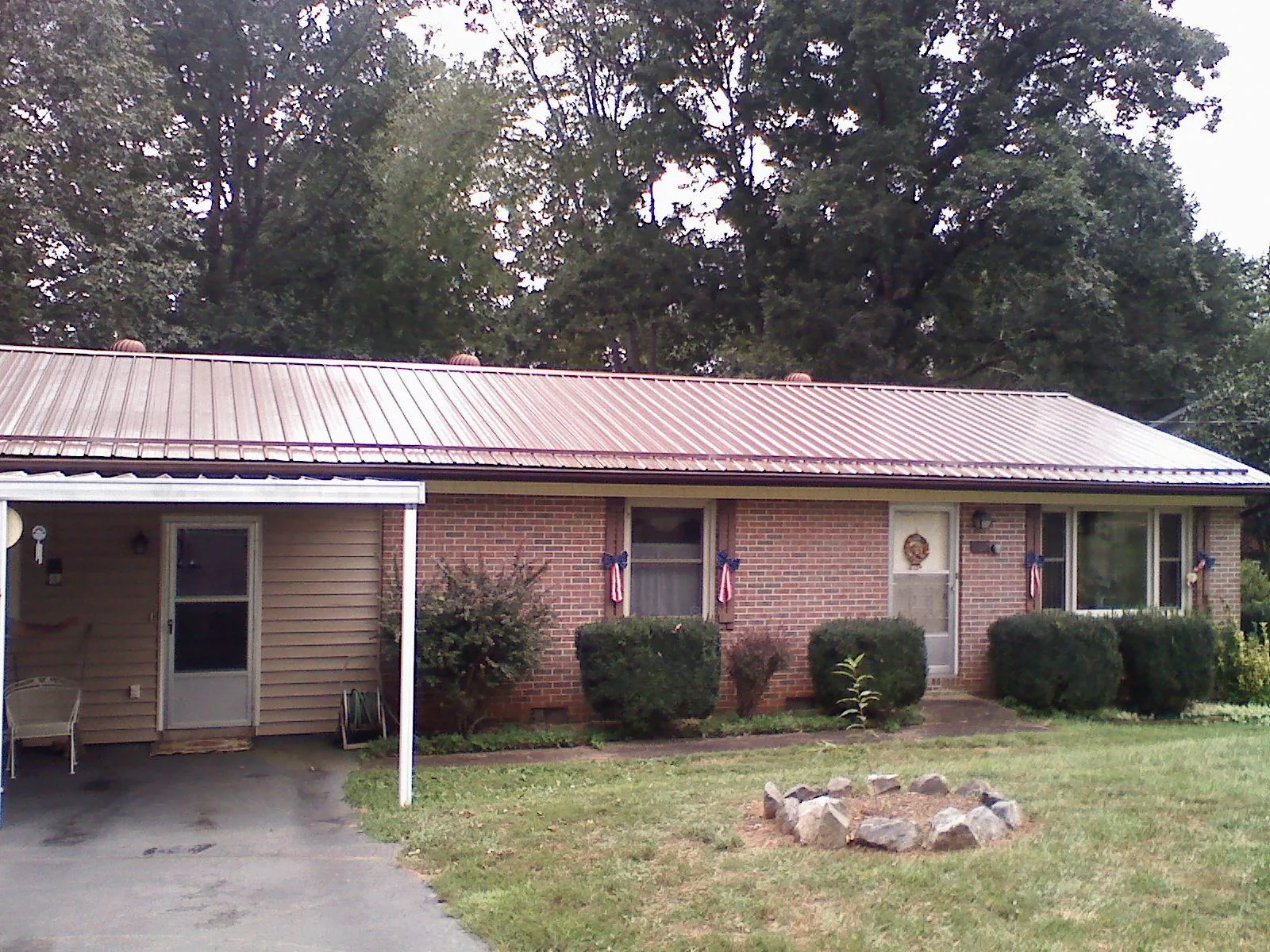 Bronze metal roof and carport on a brick ranch home — Roof Repair work by our crew in Minot