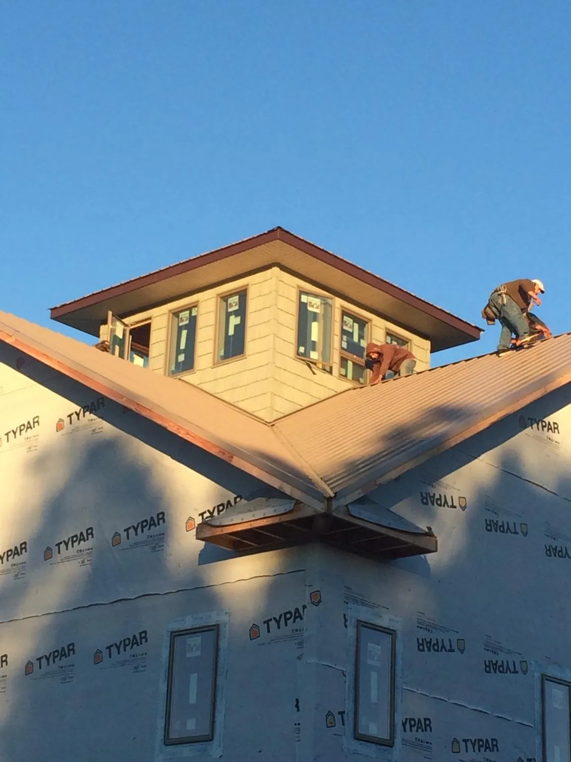 Roofers working around a rooftop cupola on a new metal roof at sunset — Roof Waterproofing in Minot by Roofing Brothers